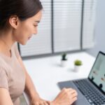 Asian young woman use laptop computer for shopping product sell online on website in smartphone.