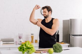 handsome and sportive man measuring muscle on hand near fresh food