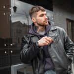 Handsome fashion urban man in trendy clothes with leather jacket in the city