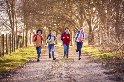 Portrait Children With School Backpacks Outdoors Running Along Countryside Track